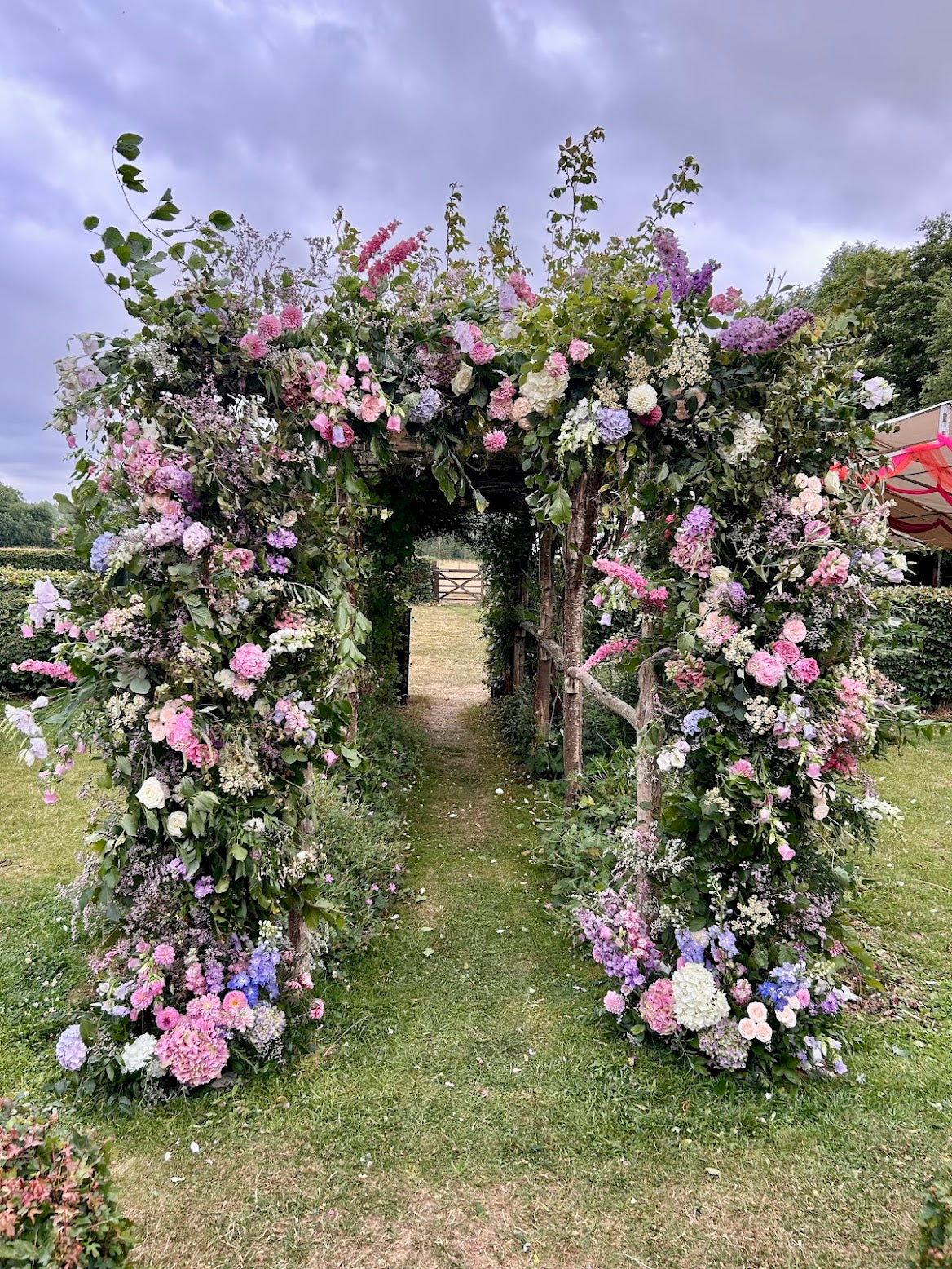 Floral archway in a garden setting with a clear sky.